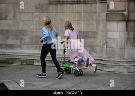 Sophie Rayworth, che si fratturò la caviglia, si dirige a Millbank House dal College Green su uno scooter il 5 luglio 2024 Foto Stock