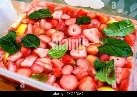 Boccetta di fragole o punch con molta frutta e foglie di menta in una ciotola quadrata, bevanda alcolica fredda da festa dalla Germania a base di frutta, vino bianco e Foto Stock