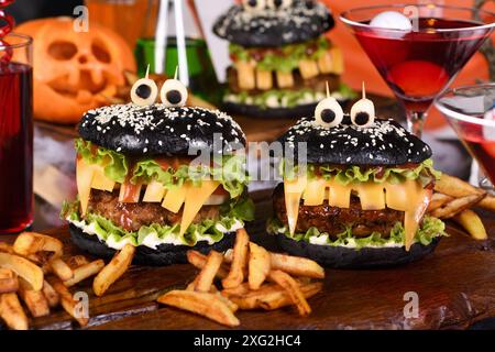 Monster Burger. Panino nero, succosa cotoletta di manzo, lattuga, cipolla, pomodoro e formaggio a forma di denti, occhi di mozzarella con olive. Decisamente una scelta... Foto Stock