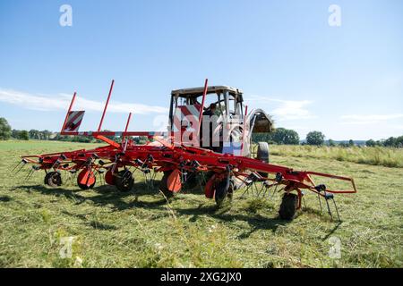 Kaltenbrunn, Germania. 6 luglio 2024. Un contadino gira il fieno in un prato tagliato mentre splende il sole. Il clima instabile di giugno ha reso il fieno un compito da snervamento quest'anno. Crediti: Pia Bayer/dpa/Alamy Live News Foto Stock