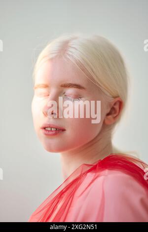 Inclusa ragazza albino che indossa il velo rosso su sfondo bianco. Verticale Foto Stock