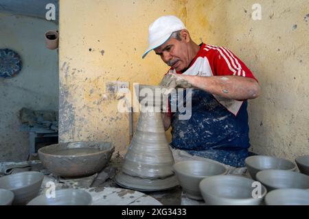 FES, Marocco - 23 marzo 2024: Un artigiano modella sapientemente l'argilla su una ruota di ceramica, circondata da ciotole fatte a mano. Uno sguardo al processo dettagliato Foto Stock