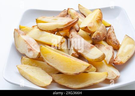 Primo piano di pezzi di patate fritte appena fatti su un pezzo di carta da forno. Concetto di cibo sano Foto Stock