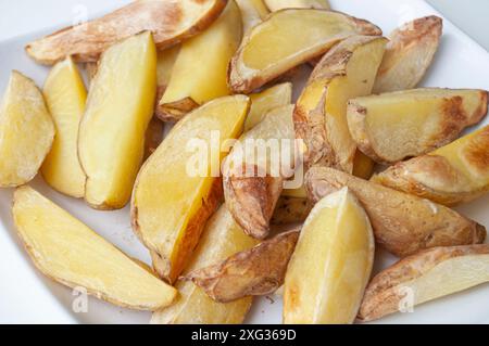 Primo piano di pezzi di patate fritte appena fatti su un pezzo di carta da forno. Concetto di cibo sano Foto Stock