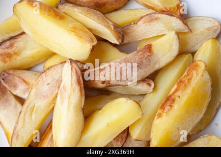 Primo piano di pezzi di patate fritte appena fatti su un pezzo di carta da forno. Foto Stock