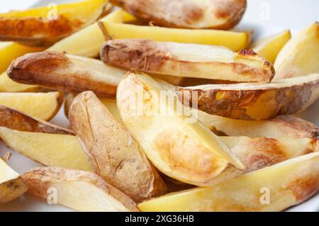 Primo piano di pezzi di patate fritte appena fatti su un pezzo di carta da forno. Concetto di cibo sano. Foto Stock