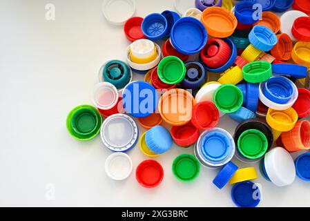 I tappi in plastica multicolore dei flaconi in plastica sono sparsi su un tavolo bianco in pile Foto Stock