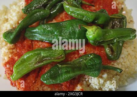 Un pasto vegetariano: miglio con salsa di pomodoro rosso e paprika e peperoni Padrón grigliati Foto Stock