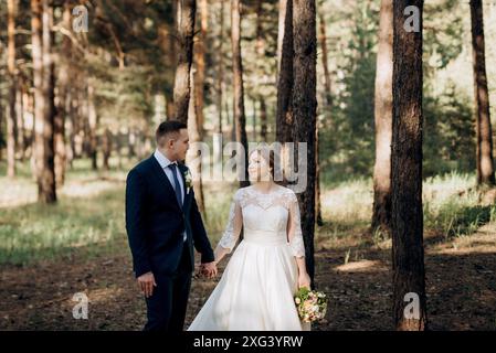 la sposa e lo sposo camminano in una pineta in una giornata intensa Foto Stock