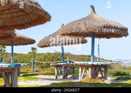 Ombrelloni esotici disposti lungo la spiaggia sabbiosa. Ombrelloni e tavoli esotici sono allestiti su una spiaggia Foto Stock