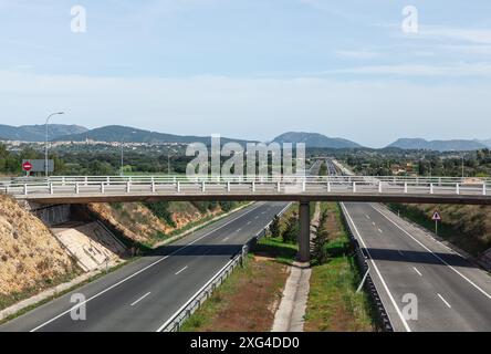 Autostrada con un ponte sopra di essa e qualche auto sopra. Strada asfaltata a Maiorca, Spagna Foto Stock