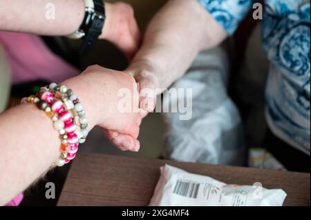 Tienen, Fiandre, Belgio, 30 giugno 2024 - mani con bracciali giocosi di una donna di 41 anni con sindrome di Down e una donna di 95 anni. Modello rilasciato Foto Stock