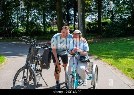 Hakendover, Brabante fiammingo, Belgio - 09 2021 39 anni donna con sindrome di Down e suo fratello felice in bicicletta. Modello rilasciato Foto Stock