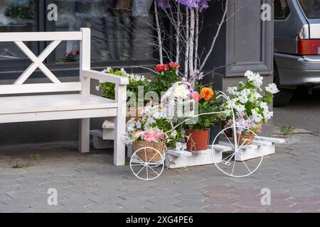 Panca bianca e bicicletta in forma di vaso di fiori all'ingresso del negozio di fiori Foto Stock