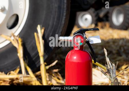 Estintore e dumper grano in campo di mais durante la mietitura. Concetto di sicurezza nelle aziende agricole, sicurezza antincendio e prevenzione degli incidenti. Foto Stock