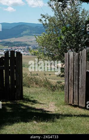 Vista panoramica attraverso il cancello di legno sulle colline e sul villaggio in una giornata di sole Foto Stock