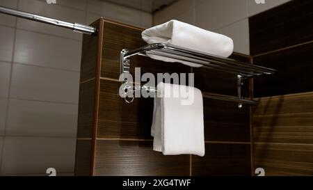 Asciugamani bianchi vicino a piastrelle di ceramica marrone. Bagno in una camera d'albergo. Asciugamano bianco nel bagno dell'hotel. Foto Stock