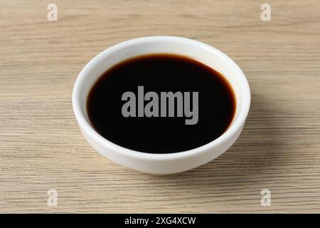 Aceto balsamico nel recipiente su un tavolo di legno chiaro Foto Stock