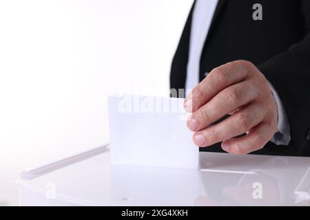 Uomo che mette il suo voto nelle urne su sfondo bianco, primo piano Foto Stock