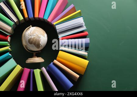 Globo circondato da molti libri colorati su sfondo verde, pianeggiante. Spazio per il testo Foto Stock