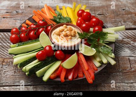 Gustoso hummus fatto in casa con ceci e verdure diverse su un tavolo di legno Foto Stock