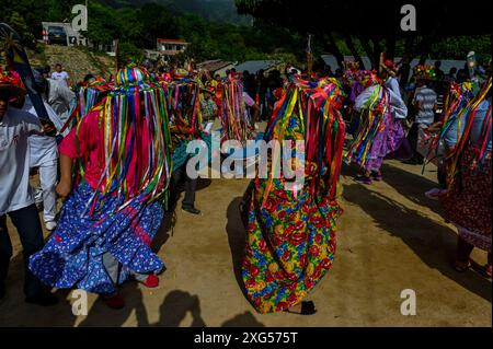 All'inizio della celebrazione del Corpus Christi a Atánquez, dipartimento di Cesar, Colombia, i gruppi di Negritos y Las Negritas ballano gioiosamente a Plaza del Coco. Las Negritas indossa abiti colorati, eleganti copricapi, mentre i Negritos indossano cappelli e spade di legno, aggiungendo un elemento dinamico e festoso al vivace patrimonio culturale della comunità Kankuamo. Foto Stock