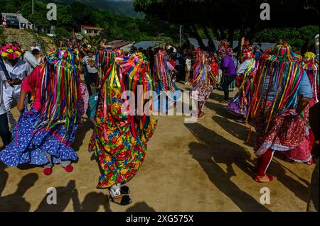 All'inizio della celebrazione del Corpus Christi a Atánquez, dipartimento di Cesar, Colombia, i gruppi di Negritos y Las Negritas ballano gioiosamente a Plaza del Coco. Las Negritas indossa abiti colorati, eleganti copricapi, mentre i Negritos indossano cappelli e spade di legno, aggiungendo un elemento dinamico e festoso al vivace patrimonio culturale della comunità Kankuamo. Foto Stock