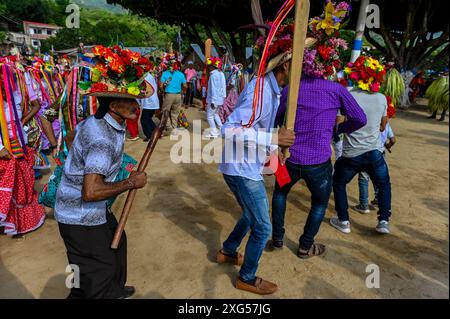 All'inizio della celebrazione del Corpus Christi a Atánquez, dipartimento di Cesar, Colombia, i gruppi di Negritos y Las Negritas ballano gioiosamente a Plaza del Coco. Las Negritas indossa abiti colorati, eleganti copricapi, mentre i Negritos indossano cappelli e spade di legno, aggiungendo un elemento dinamico e festoso al vivace patrimonio culturale della comunità Kankuamo. Foto Stock