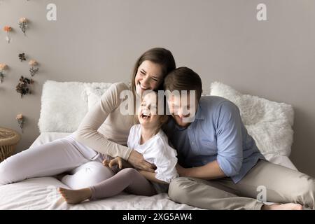 I giovani genitori che ridono passano il tempo con la figlia in età prescolare Foto Stock