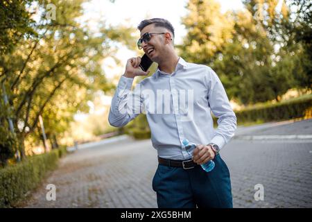 Si vede un uomo in piedi in una strada urbana trafficata, impegnato in una conversazione telefonica. Sembra concentrato sulla sua telefonata. Foto Stock