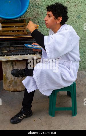 Giovane messicano che mangia tacos per strada Foto Stock