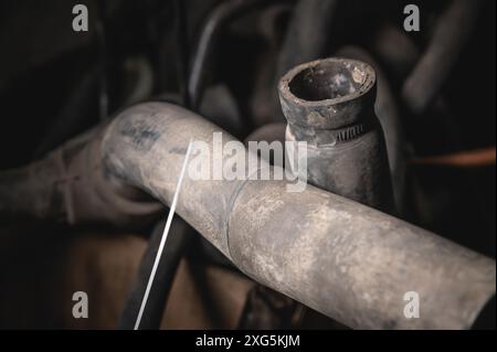 Tubi e tubi flessibili in gomma che collegano il radiatore del veicolo al motore, vista del motore dal basso. vecchi tubi flessibili del sistema di raffreddamento dell'auto usurati Foto Stock