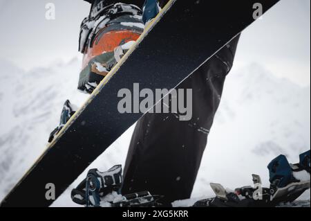 Primo piano della mano di un uomo, regolando gli sci sullo sfondo della neve e di altre cose, mettendo le pelli sulla pista. Tema scialpinismo nel Foto Stock