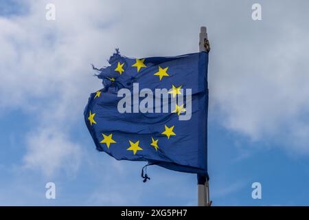 Una bandiera UE lacerata soffia al vento con alcune nuvole sullo sfondo, viste a Pevensey Bay, East Sussex, Inghilterra, Regno Unito Foto Stock