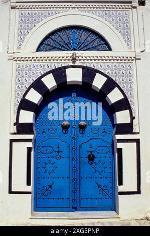 La Tunisia, Sidi Bou Said. Decorazioni tradizionali porta blu e arco, entrata in una casa privata. La porta alta battenti data dal momento in cui gli ospiti sono arrivati a cavallo. Foto Stock