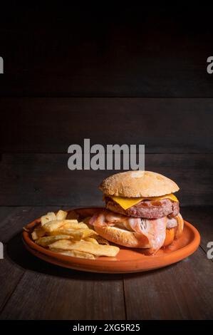 Hamburger di manzo alla griglia di prima qualità con pancetta, formaggio e patatine fritte. Delizioso hamburger americano su sfondo di legno. Fotografia di alta qualità Foto Stock