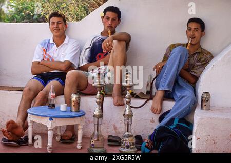 La Tunisia, Sidi Bou Said. Giovani uomini tunisini di fumare un narghilè presso il Cafe Sidi Sha'divieto. Foto Stock