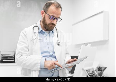 Medico di sesso maschile con rivestimento bianco e stetoscopio utilizzando tablet, connessione di rete in sala d'ospedale, tecnologia medica concetto di rete. Alta qualità Foto Stock