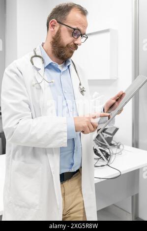 Medico di sesso maschile con rivestimento bianco e stetoscopio utilizzando tablet, connessione di rete in sala d'ospedale, tecnologia medica concetto di rete. Alta qualità Foto Stock