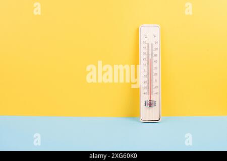 Termometro su sfondo giallo e blu, misurazione della temperatura, previsioni meteo, riscaldamento globale e discussione sull'ambiente, estate Foto Stock