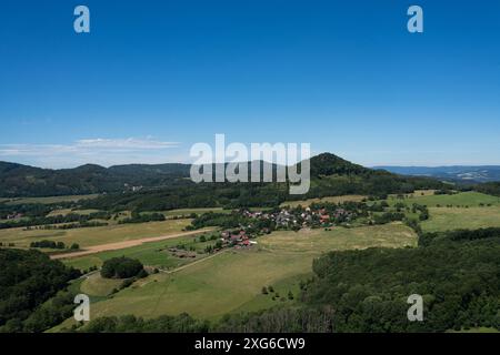 La collina del castello di panna e il villaggio di Řepčice nelle pianure centrali della Boemia. Paesaggio di campagna collinare di origine vulcanica in estate. Cielo blu. Foto Stock