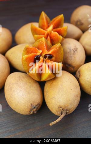 Tagliare splendidamente la frutta della Sapodilla su un mucchio di frutta intera Foto Stock