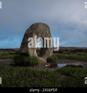 Una vista della brughiera della Cornovaglia della pietra foderata Mên-an-Tol, con il vano motore di Greenburrow raffigurato al centro del foro in lontananza. Foto Stock