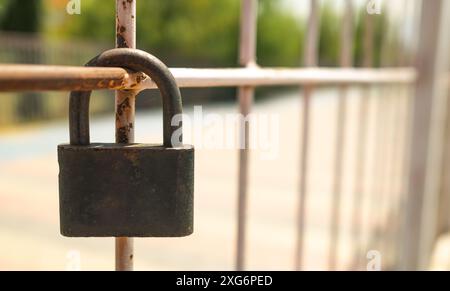 Lucchetto sulla recinzione esterna da vicino. Lucchetto in metallo arrugginito sulla recinzione con sfondo sfocato e spazio di copia Foto Stock