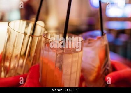 Primo piano di tre persone che sorseggiano cocktail al bar, drink e cocktail con spazio per testo Foto Stock