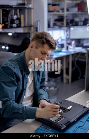 Riparazioni e diagnostica guasti del computer portatile in un centro di assistenza professionale. Master elettronico professionale in officina, utilizzando strumenti o strumenti diversi Foto Stock