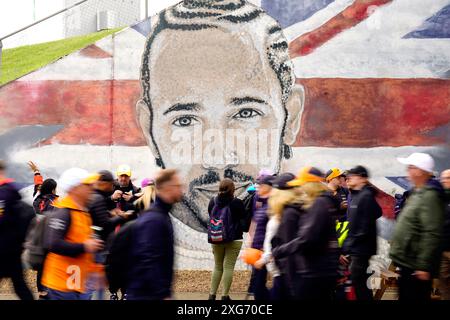 Gli spettatori passano un murale di Lewis Hamilton prima della gara al circuito di Silverstone, Northamptonshire. Data foto: Domenica 7 luglio 2024. Foto Stock