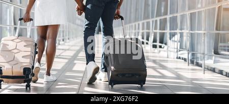 Coppia che cammina attraverso il terminal dell'aeroporto con bagagli, corti Foto Stock