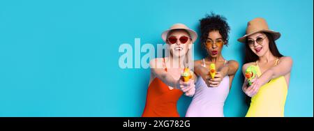 Tre donne in costumi da bagno giocano con le pistole ad acqua Foto Stock