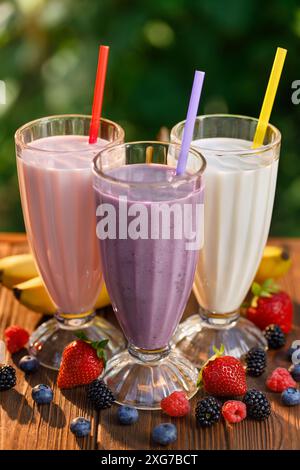 set di frullati al gusto di fragola, banana e mirtillo o frullato in bicchieri sul tavolo all'aperto Foto Stock